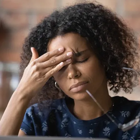 A woman with a headache rubbing at the spot between her eyes