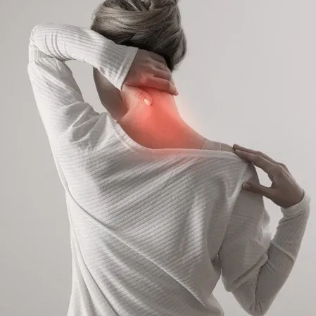 A woman with neck pain massaging her neck and shoulder